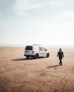 Woman and her van on a beach in the UK